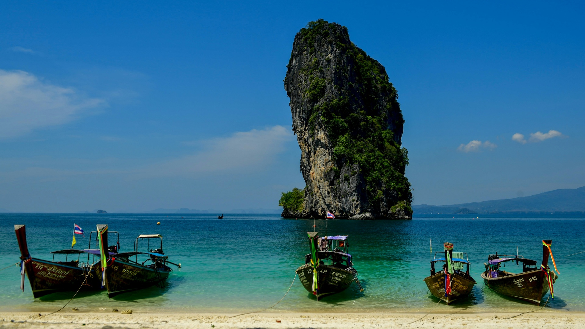 Playa de Phuket con bote tradicional tailandés en aguas turquesa