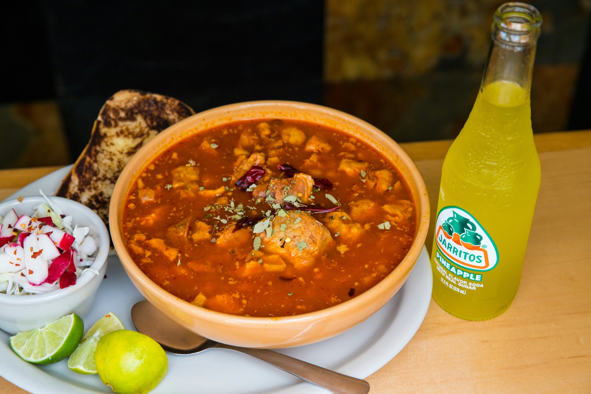 Plato de pozole rojo servido con rábano y tostadas